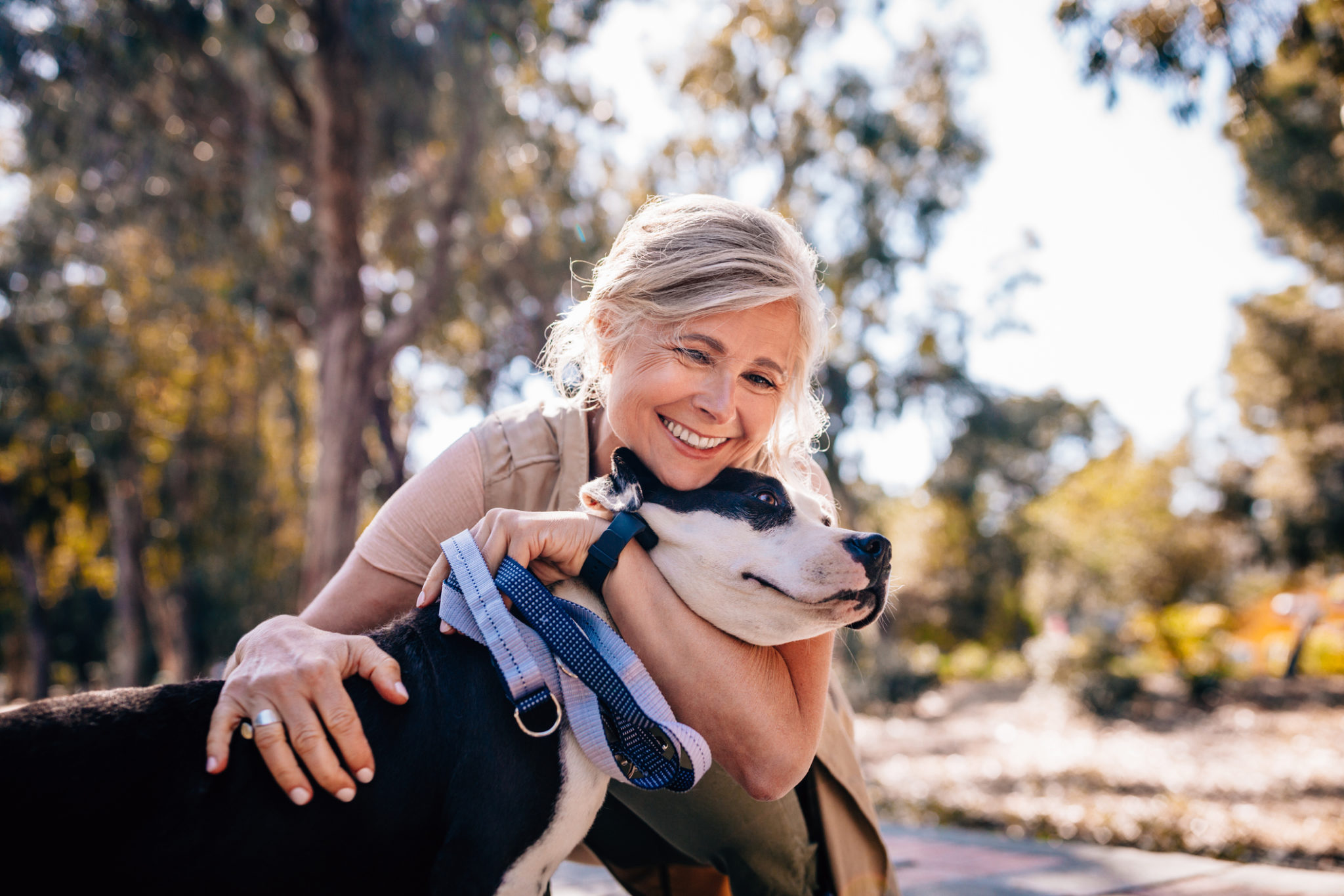 Affectionate mature woman embracing pet dog in nature White Teeth FTW!